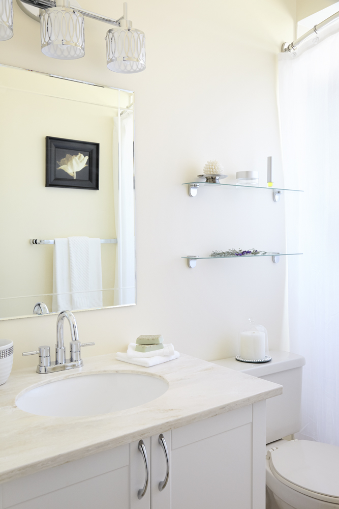 a small warm white bathroom with shiny chrome accents and a warm sandy white countertop with white sink
